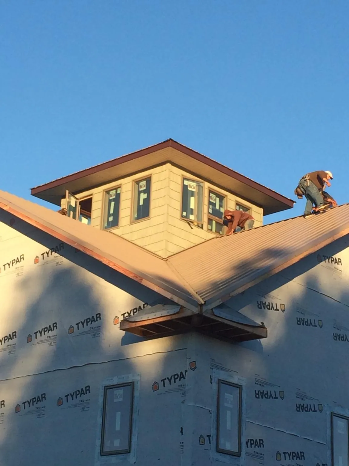 Roofers working around a rooftop cupola on a new metal roof at sunset — Roof Waterproofing in Proctor by Roofing Brothers